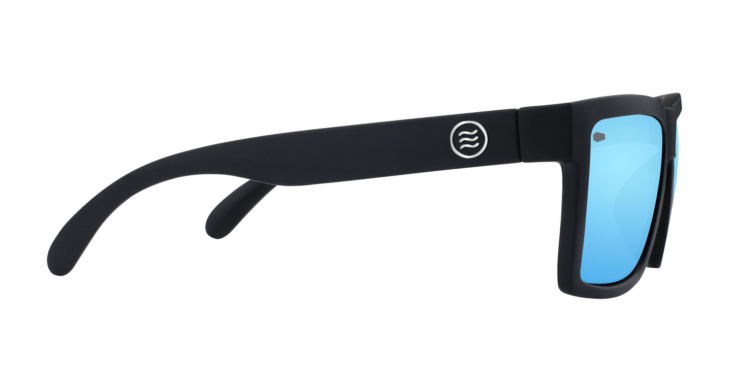 The Neven Eyewear Montauk sunglasses feature black frames with thick arms and a white circular logo, plus mirrored blue lenses for beach style. They're shown side-on against a white background.
