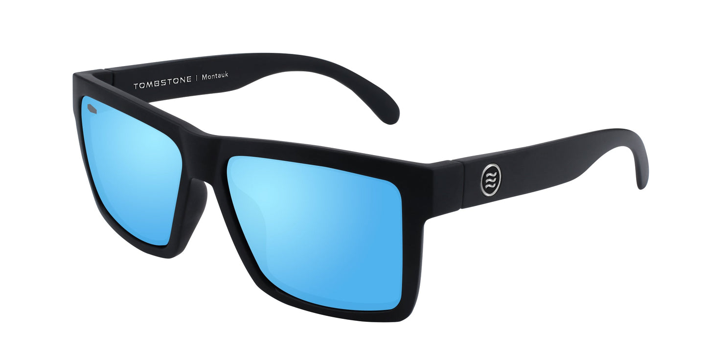 A pair of Montauk glasses from Neven Eyewear featuring black frames and large square mirrored blue lenses, with "TOMBSTONE Matte Black" printed inside the arm and a wave logo outside—ideal for stylish beachwear.