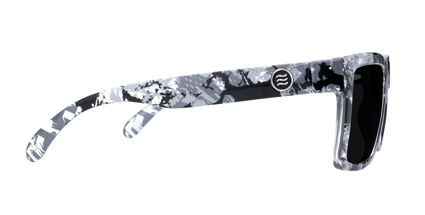 Neven Eyewear's South Shore sunglasses feature a black, white, and gray camo frame with dark lenses and a circular wavy-line logo on the arm near the hinge, all set against a white background.