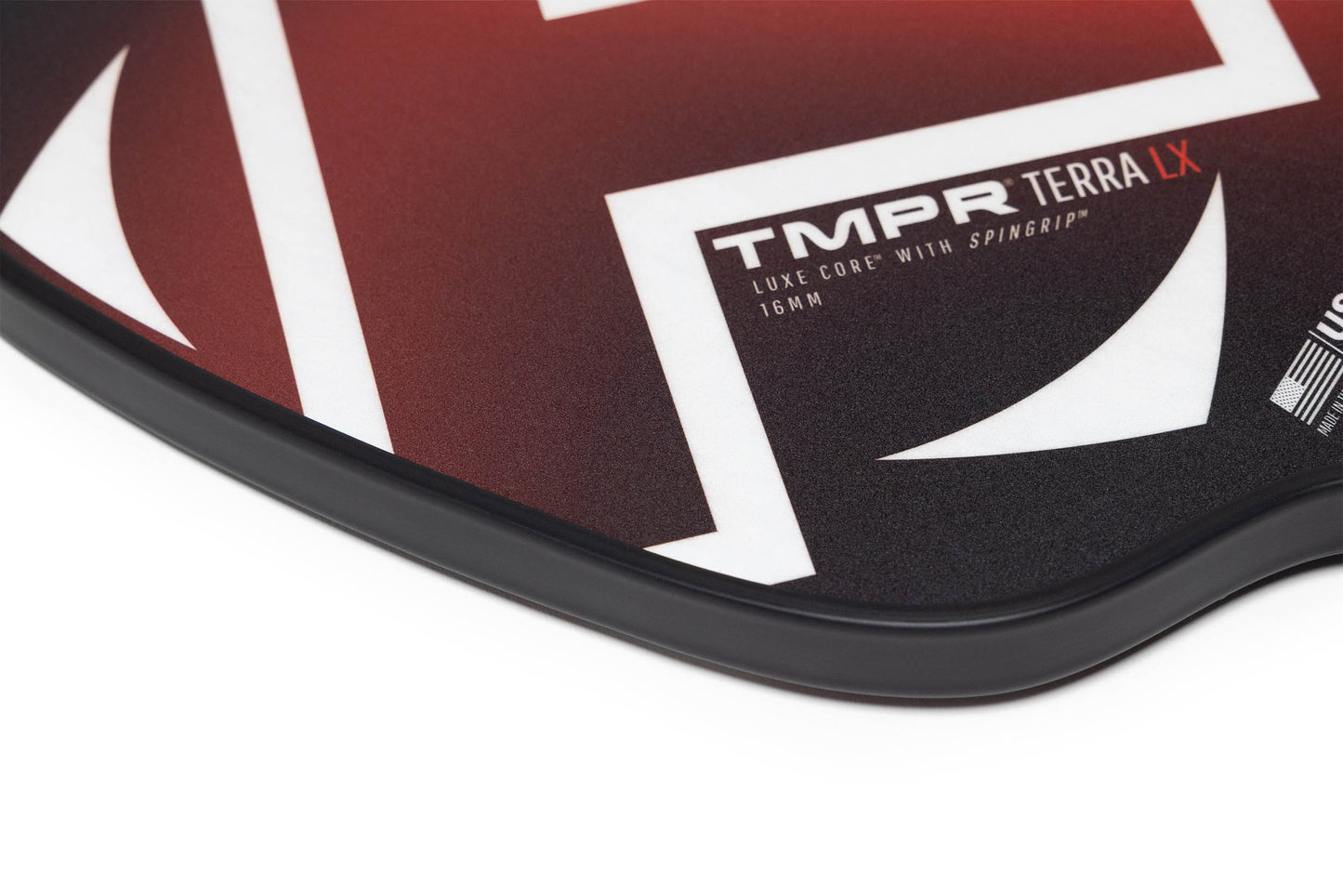 Close-up of the TMPR Sports Terra LX pickleball paddle, featuring a red, black, and white geometric design. Its curved edge highlights textured details and modern style, with vibration dampening technology for improved play.