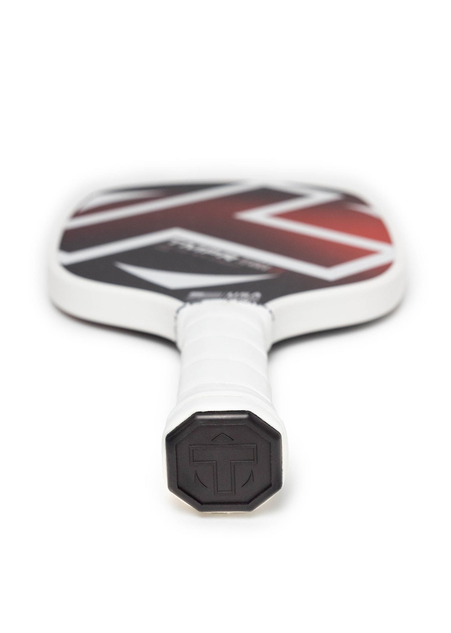A close-up of a TMPR Sports Terra LX pickleball paddle shows its white grip-taped handle and striking geometric face, featuring advanced vibration dampening technology and the signature T logo on the cap.