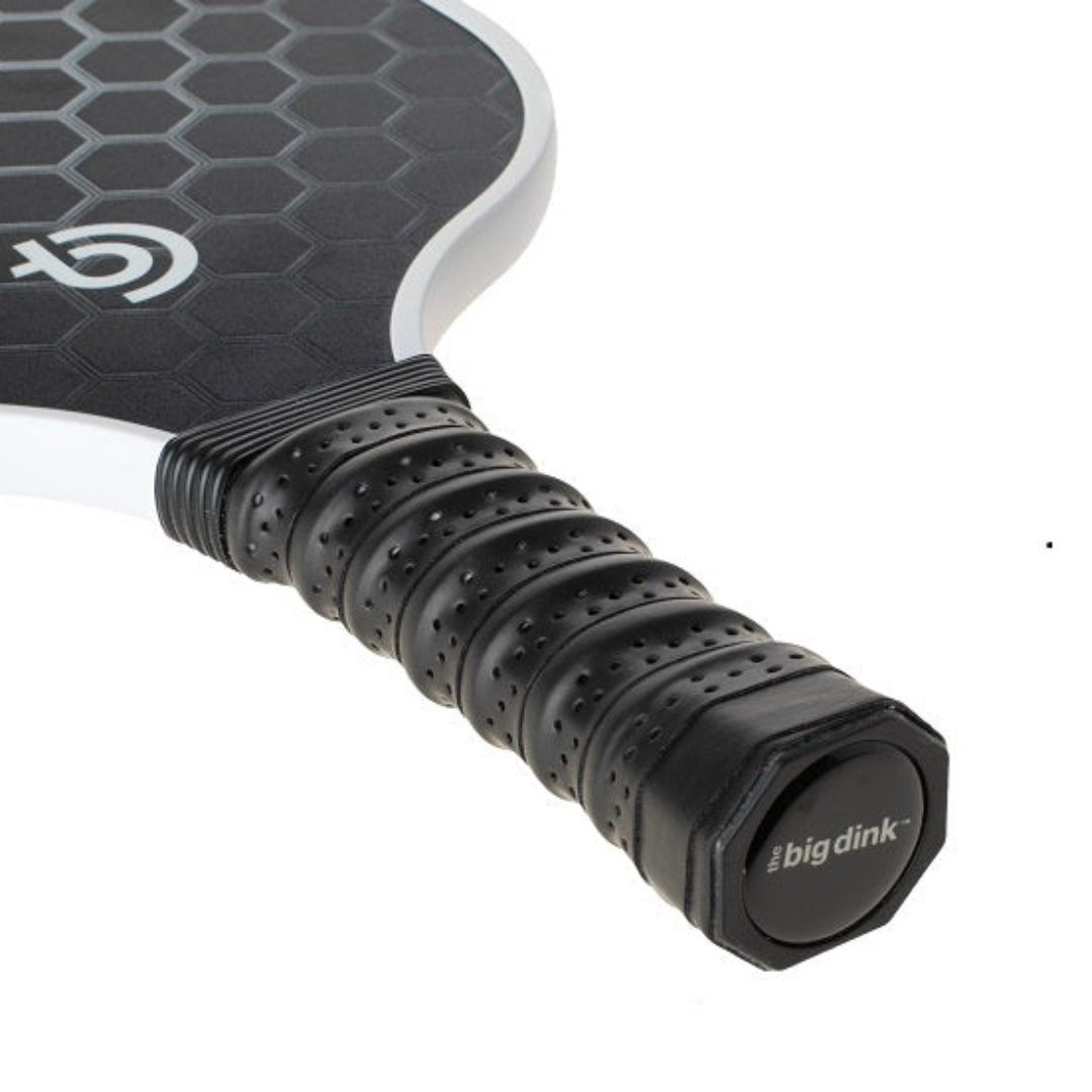 Close-up of The Big Dink Bundle by The Big Dink—a black carbon fiber pickleball paddle with hexagonal textured face, perforated grip, branded cap, and white edge guard. Ideal budget-friendly choice for beginner players.