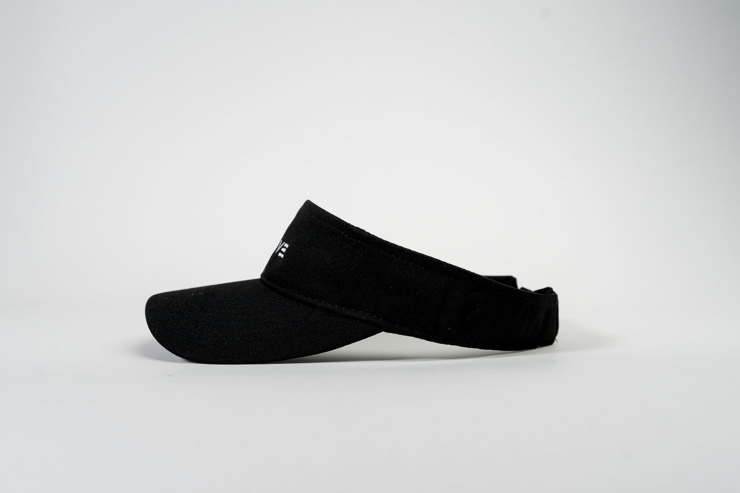 The Thrive Pickleball Thrive Elite Tour Visor is shown in black against a white background, featuring a curved brim, adjustable strap, and minimalist low profile design positioned in profile.