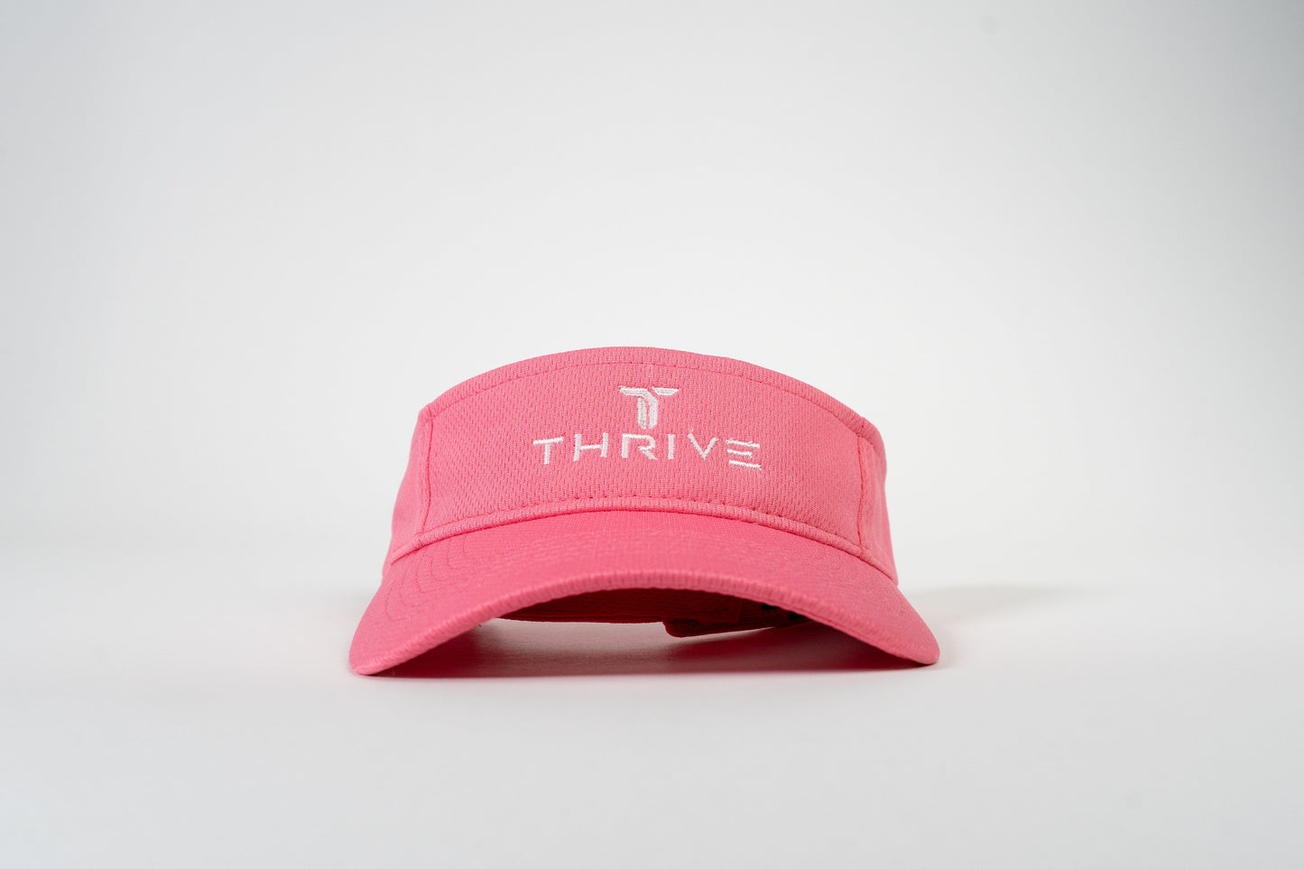 The Thrive Elite Tour Visor by Thrive Pickleball is a pink, low-profile visor with “THRIVE” and a stylized T logo embroidered in white on the front, shown centered against a plain light gray background.