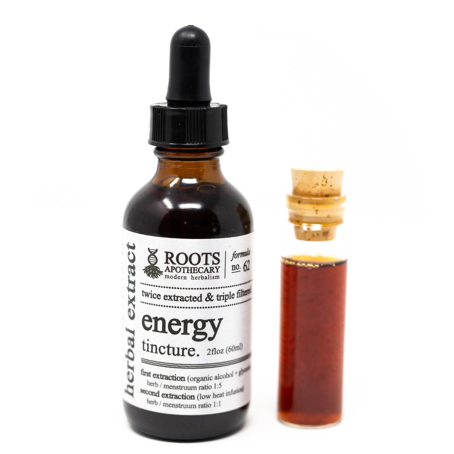 A brown glass dropper bottle labeled Roots Apothecary Energy Tincture stands beside a small vial of reddish liquid with a cork, the white label with black text displayed against a plain white background.