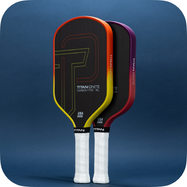 Three Titan Pickleball Titan Ignite 16L paddles stand upright against a dark blue background. Each features a unique accent color—yellow, orange, or purple—with white grips, carbon fiber surfaces, and pro-level spin performance.