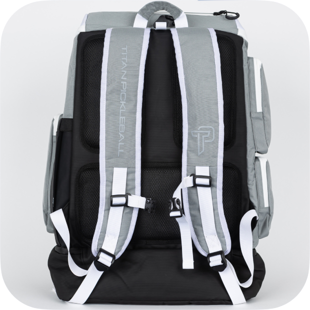 The Titan Pickleball Backpack by Titan Pickleball features a gray and black design with white trim, padded mesh-lined straps, multiple compartments, back panel TITAN PICKLEBALL branding with TP logo, adjustable straps, and a top handle.