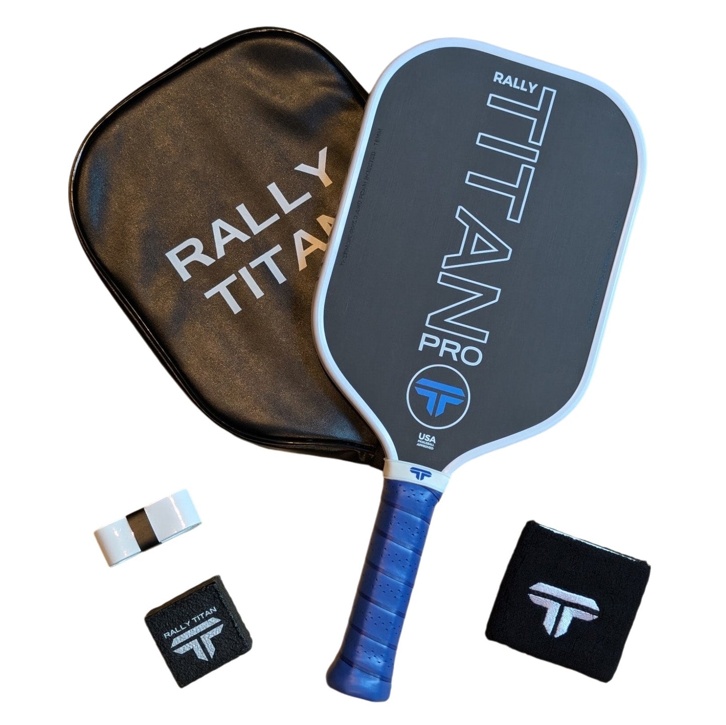 A white and blue-accented Rally Titan Pro 16MM pickleball paddle with T700 Titan carbon friction surface and foam-injected walls sits by its black case, plus two wristbands and a white overgrip—all branded with the Rally Titan Pickleball logo.