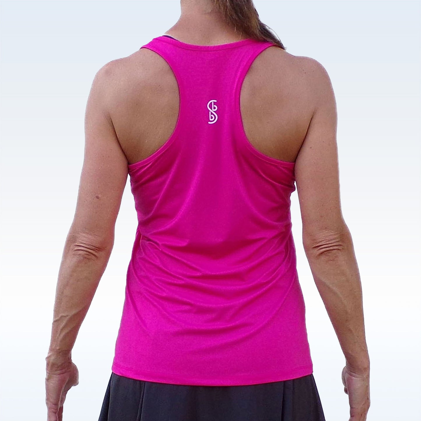 A woman wears the Pickleball Bella PB Racerback Tank Pink, featuring moisture-wicking fabric and SPF 50+ UV protection—ideal for active outdoor days.