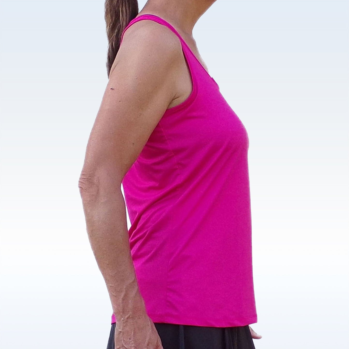 A woman wearing the Pickleball Bella PB Racerback Tank in Pink, featuring SPF 50+ UV protection.