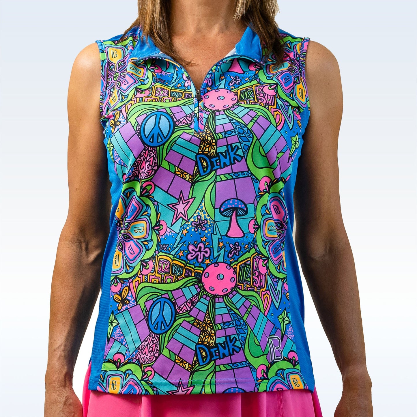 A woman wears the Pickleball Bella PB 1/4 Zip Sleeveless Groovy top, featuring a bright psychedelic pattern with peace signs, mushrooms, stars, and "DINK" in blue, green, pink, and purple—perfectly playful for pickleball.