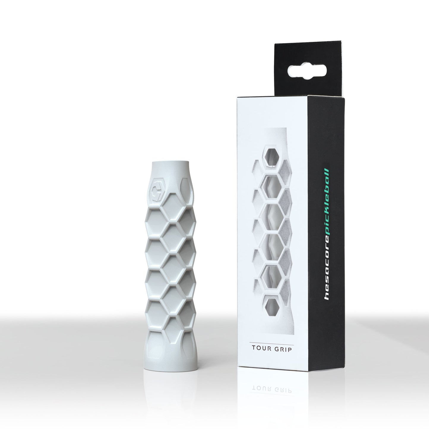 A white, sweat-absorbing Hesacore Grip (5.25" Regular Feel) stands upright beside its black and white box, which features a window showing the Pickleball Grip inside. The box displays "TOUR GRIP" and "hexatorcpickleball" in green and white.