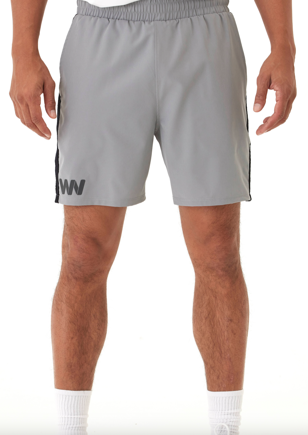 A person faces forward, wearing Wringer Wear Mojave Performance Shorts 6" Lined in light gray with black side stripes and a WW logo on the left thigh. Made from moisture-wicking fabric, the shorts are paired with white crew socks. Waist to knee view only.