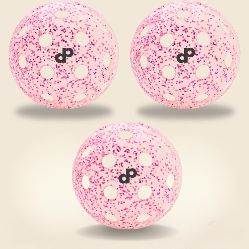 Three Pink Glitter-Infused Pickleball Balls by Dope Pickleball Co. with white holes, magenta speckles, and black dp logos float on a beige background, arranged with two at the top and one centered below.