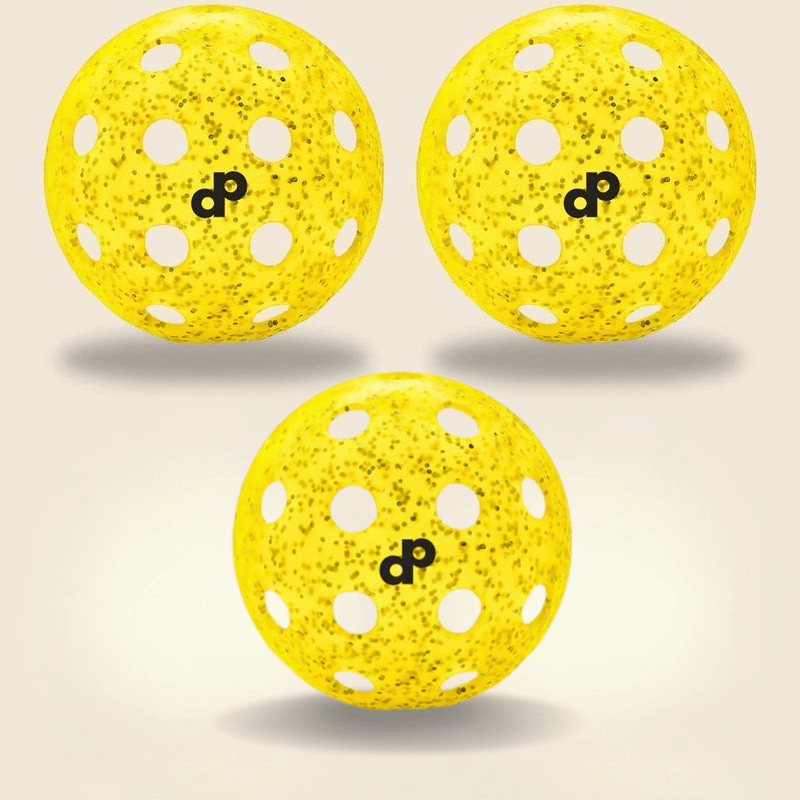 Three Dope Pickleball Co. Yellow Glitter-Infused Pickleball Balls, each with white holes, speckled pattern, and a black "dp" logo, are arranged in a triangle and cast soft shadows on a pale beige background for enhanced visibility.
