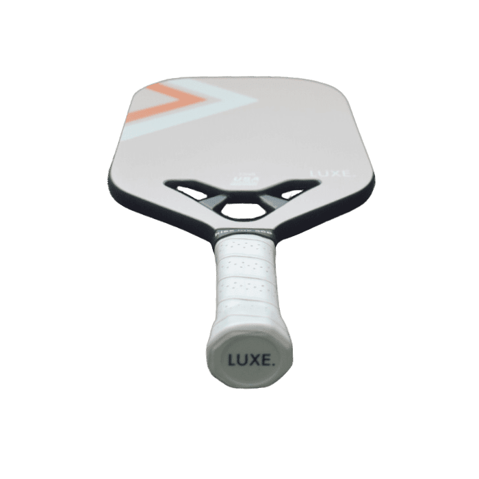 The LUXE Pickleball Draft paddle features a white carbon fiber surface with an orange geometric design near the top, a perforated white grip, and "LUXE." printed on the end cap, shown against a plain white background.