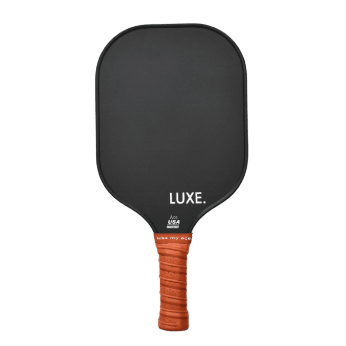The Aesthetic Solids - Ace by LUXE Pickleball is a black, rectangular paddle with rounded edges and a textured orange grip sporting “kiss my ace.” “LUXE.” is printed in white. USA Pickleball Approved for tournament play.