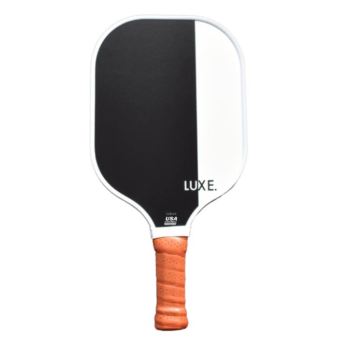 The Dipped - Leisure paddle by LUXE Pickleball features a black and white fiberglass surface, rounded edges, a tan textured grip, and a white LUXE. logo. It has a durable honeycomb polymer core and is set against a plain light gray background.
