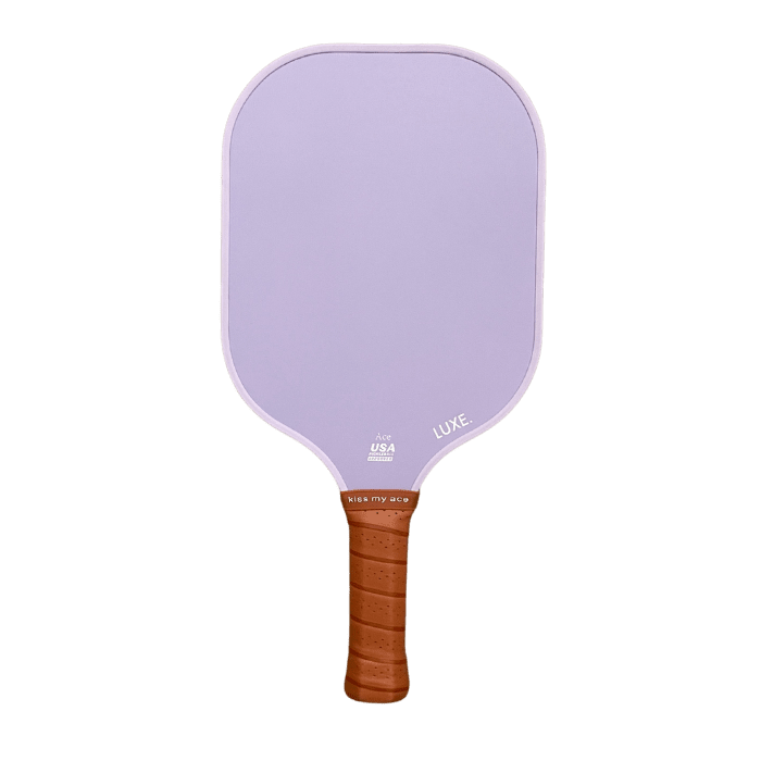 A light purple carbon fiber Core Collection paddle from LUXE Pickleball features a rectangular, rounded-edge shape, a brown textured grip, and small white text: "USA PICKLEBALL," "LUXE.," and "VIBE MY AURA." Paddle shown on a plain white background.