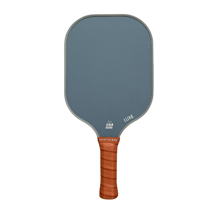 The Core Collection by LUXE Pickleball features a carbon fiber paddle with a rectangular, muted blue-gray face, rounded corners, textured USA and LUKE markings, and a brown perforated "kick my ace" grip. USA Pickleball Approved.