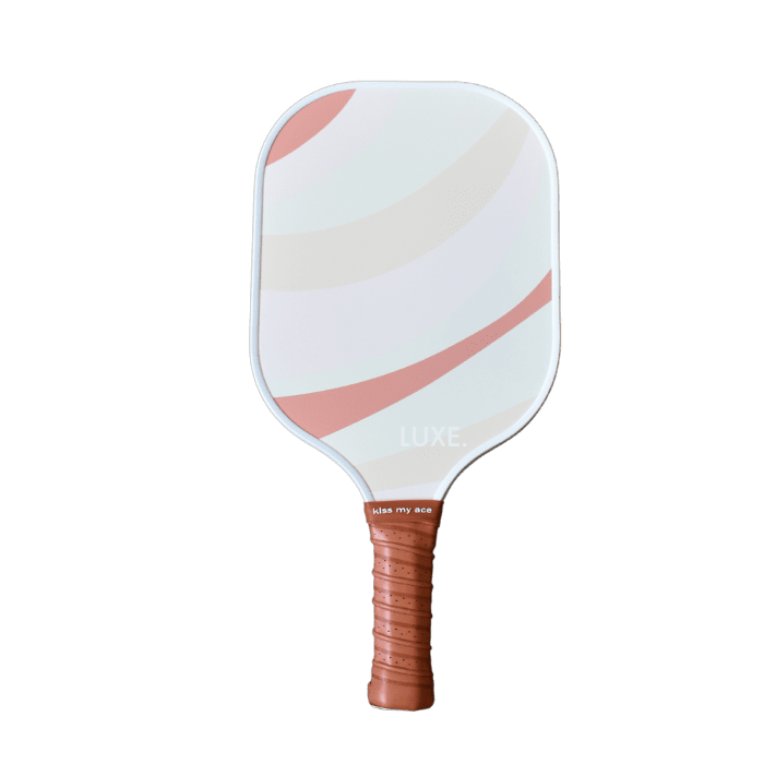 The Pink and Rust paddle by LUXE Pickleball features a white face with blush pink and beige swooshes, a textured brown grip, and the words "LUXE." and "kiss my ace" printed, making it a stylish choice for your pickleball game.