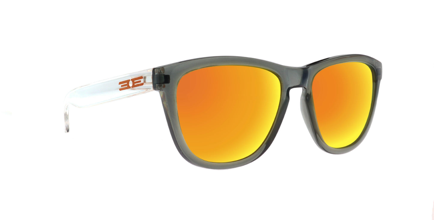 Epoch Eyewear’s VIBE sunglasses feature transparent gray frames, bright orange mirrored lenses, and clear temples with an orange "3E" logo by the hinges. Luxury style shown on a white background.