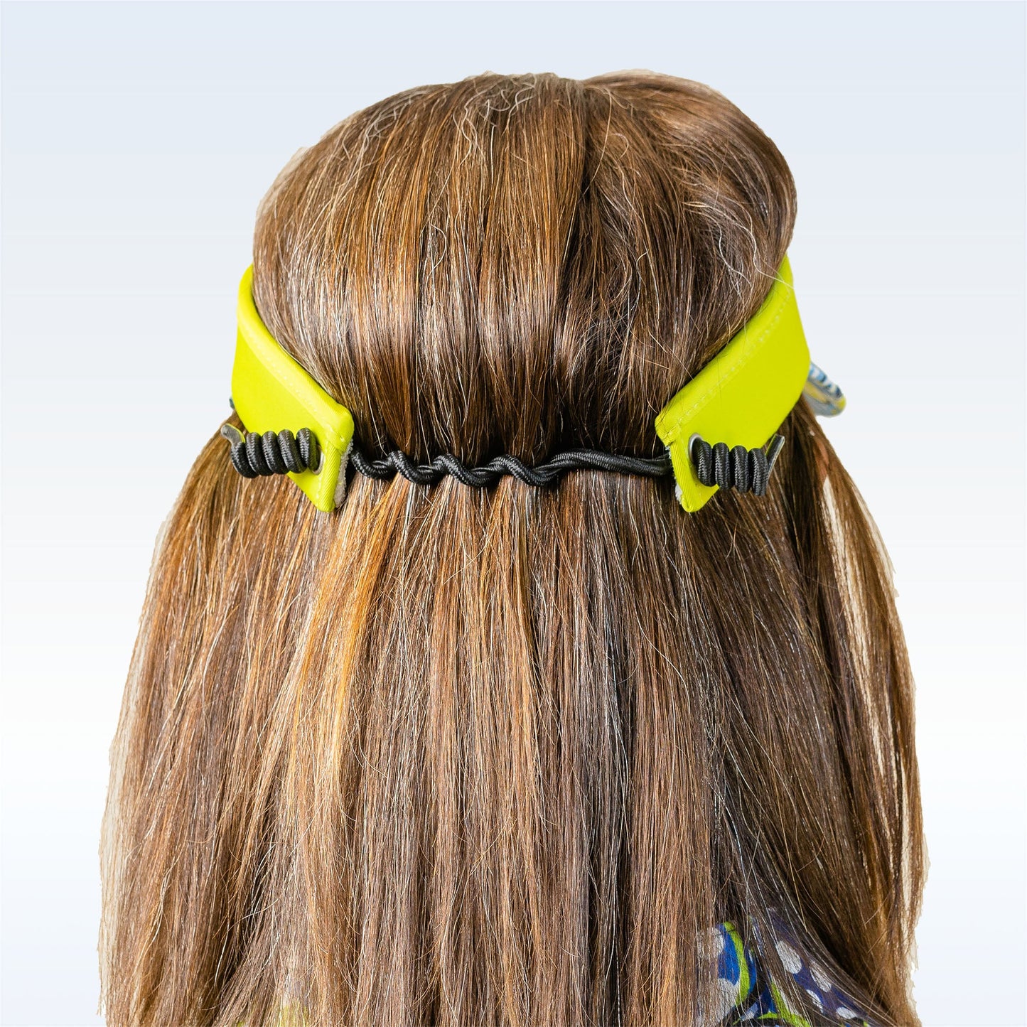 A person with straight, light brown hair is shown from behind wearing the Pickleball Bella PB Visor Dink 1, a lightweight yellow headband with black elastic and wavy accents, holding their hair in place against a plain backdrop.