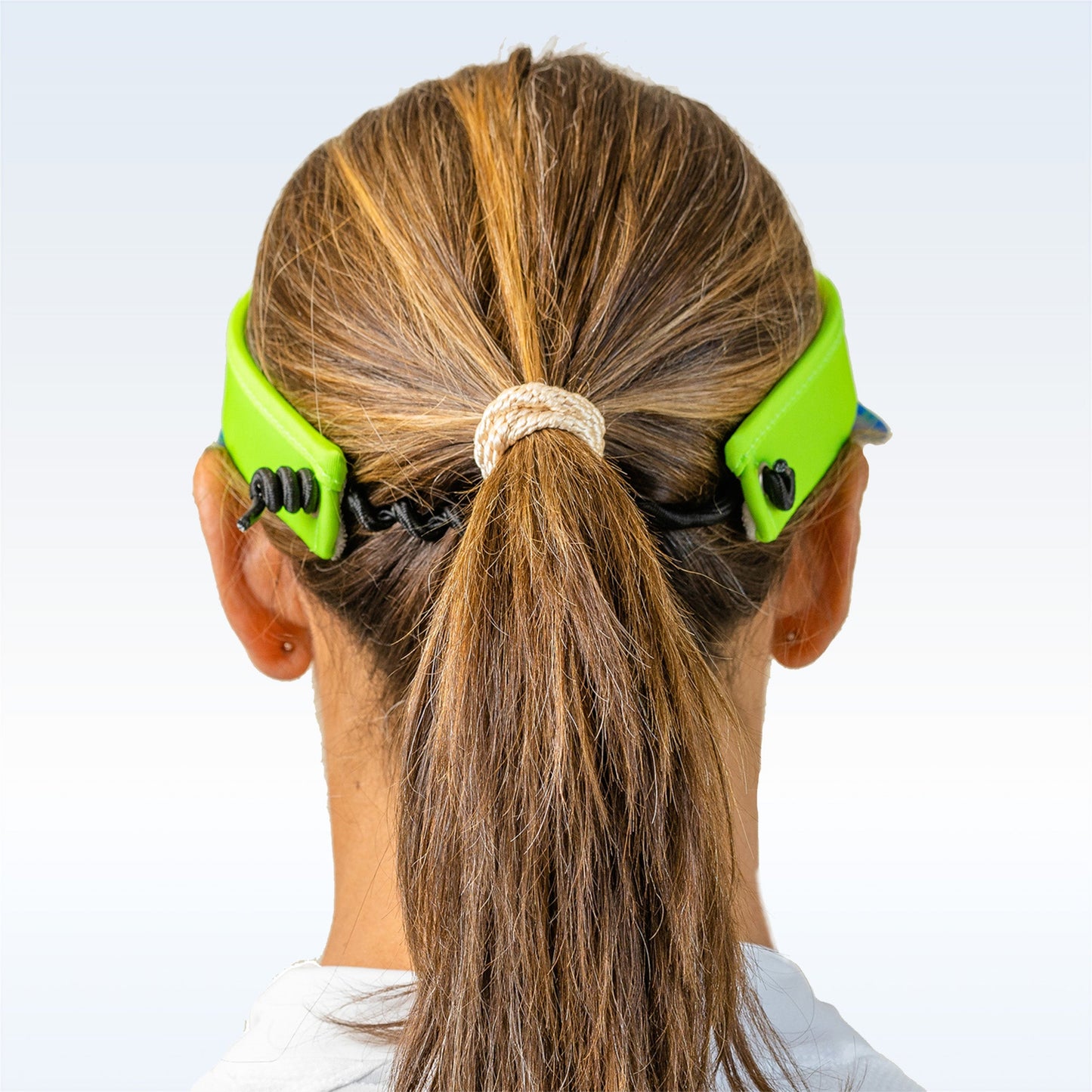 A person with light brown hair in a ponytail, secured with a beige hair tie, is shown from behind wearing the Pickleball Bella PB Visor Patience Grasshopper, paired with a face mask.