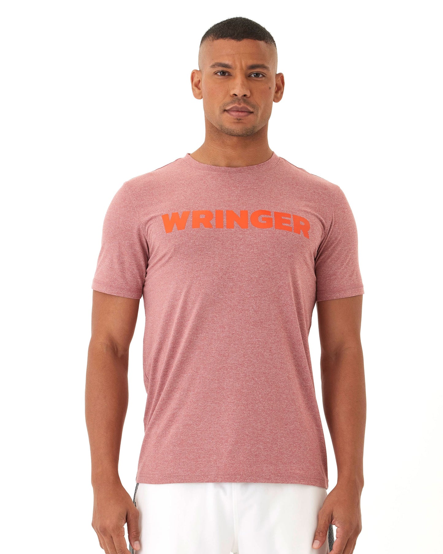 A man faces forward wearing Wringer Wear's Men's Short Sleeve WRINGER T-shirt in heathered red, featuring bold orange "WRINGER" lettering. The breathable athletic tee is paired with white shorts against a plain white background.