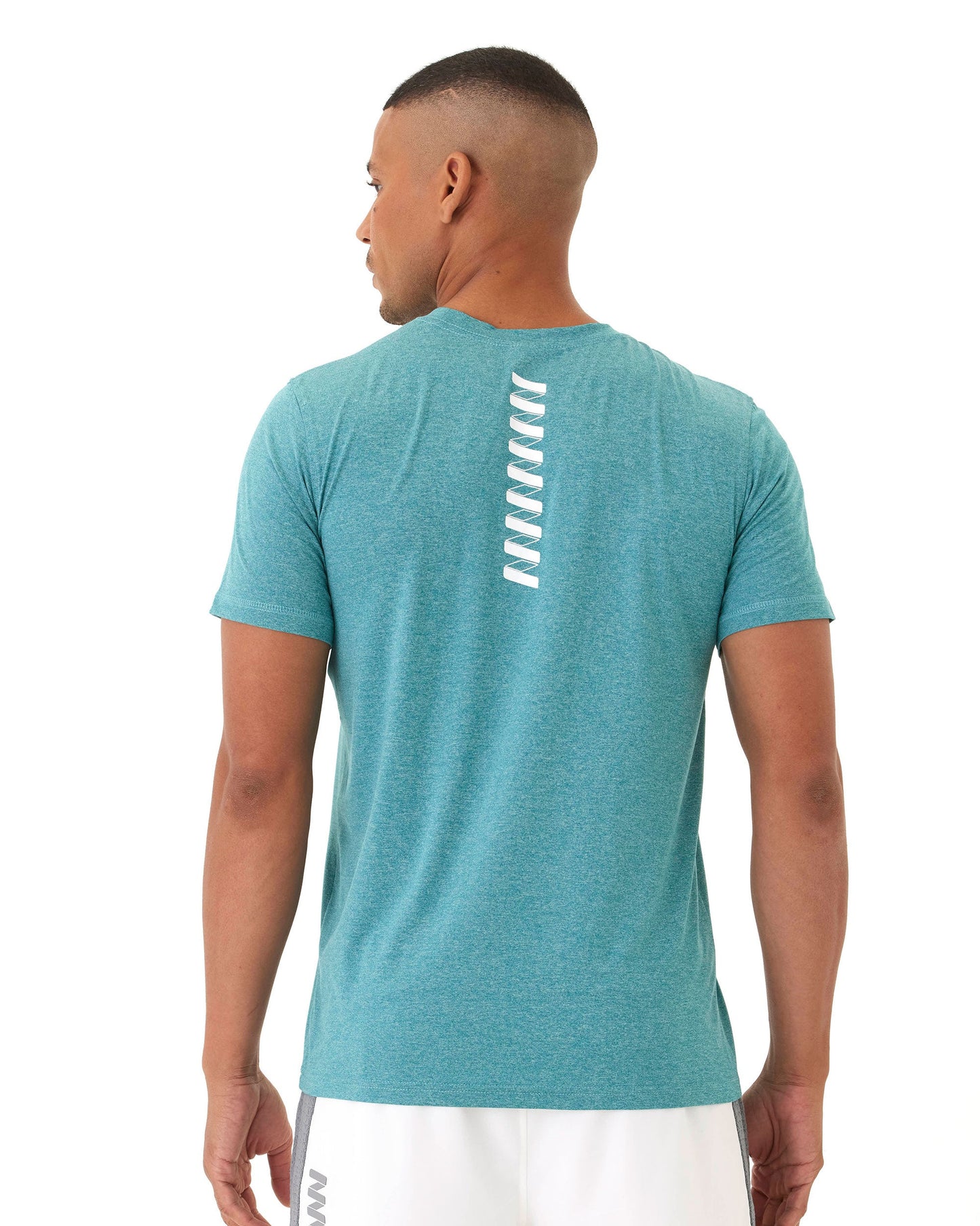 A man wears the Wringer Wear Men's Short Sleeve WRINGER T-shirt in teal, featuring white wave-like patterns on the upper back, and white shorts. The athletic fit tee is made from breathable lightweight fabric. Background is clean and white.