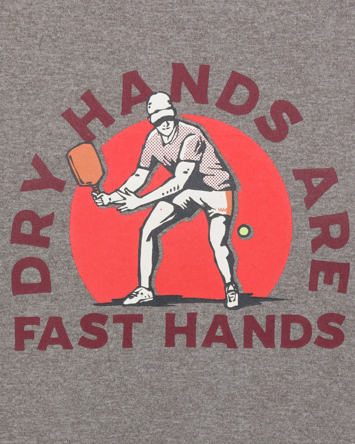 The Wringer Wear Men's Short Sleeve Fast Hands Graphic Tee features a heather gray athletic cut with a striking pickleball player graphic and the motto "DRY HANDS ARE FAST HANDS." Perfect for performance on and off the court.