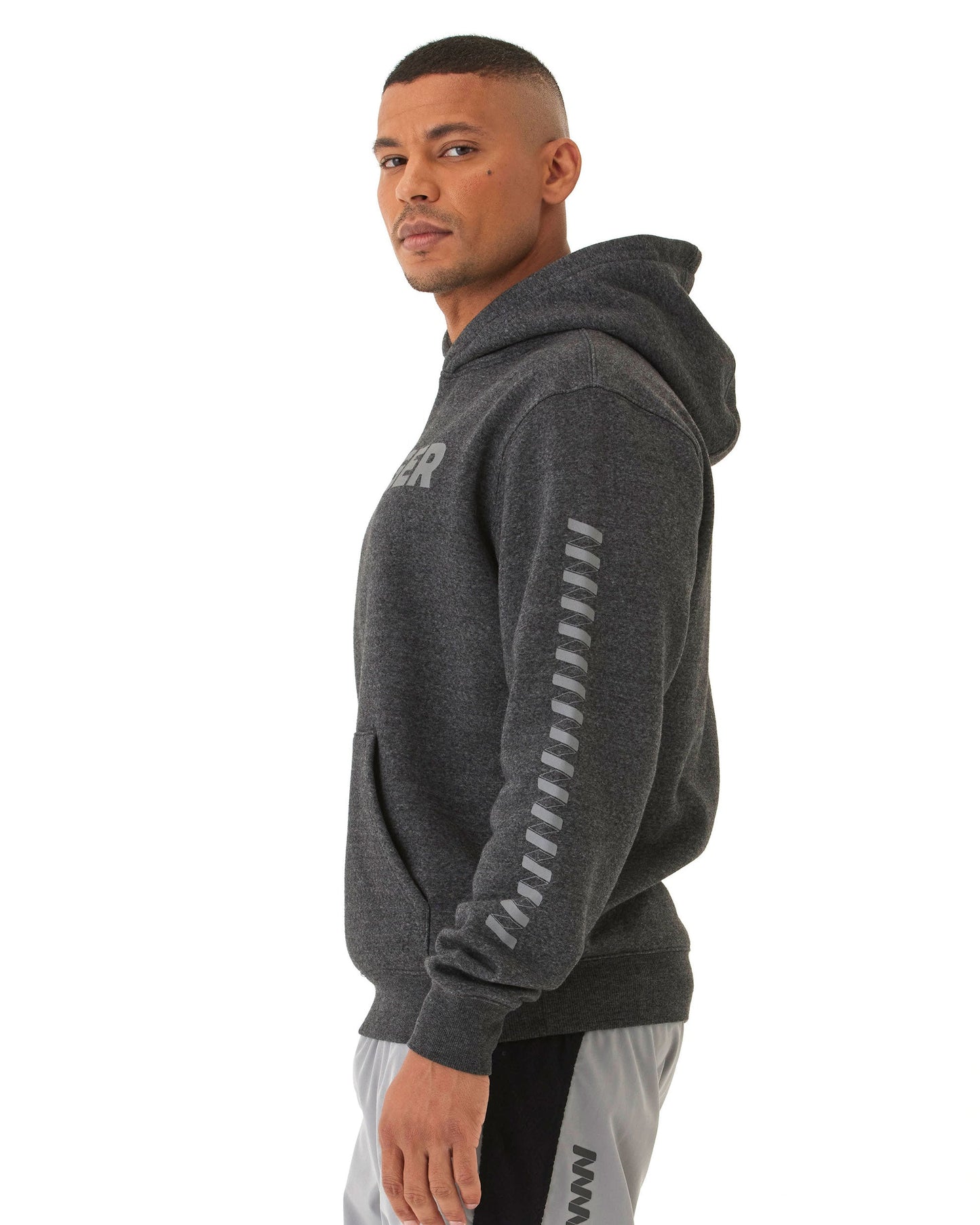 A man faces left wearing a dark gray Wringer Wear Men's Core Wringer Graphic Hoodie with light gray sleeve stripes, partial chest logo, and front pocket, paired with light gray athletic shorts featuring a dark side design.