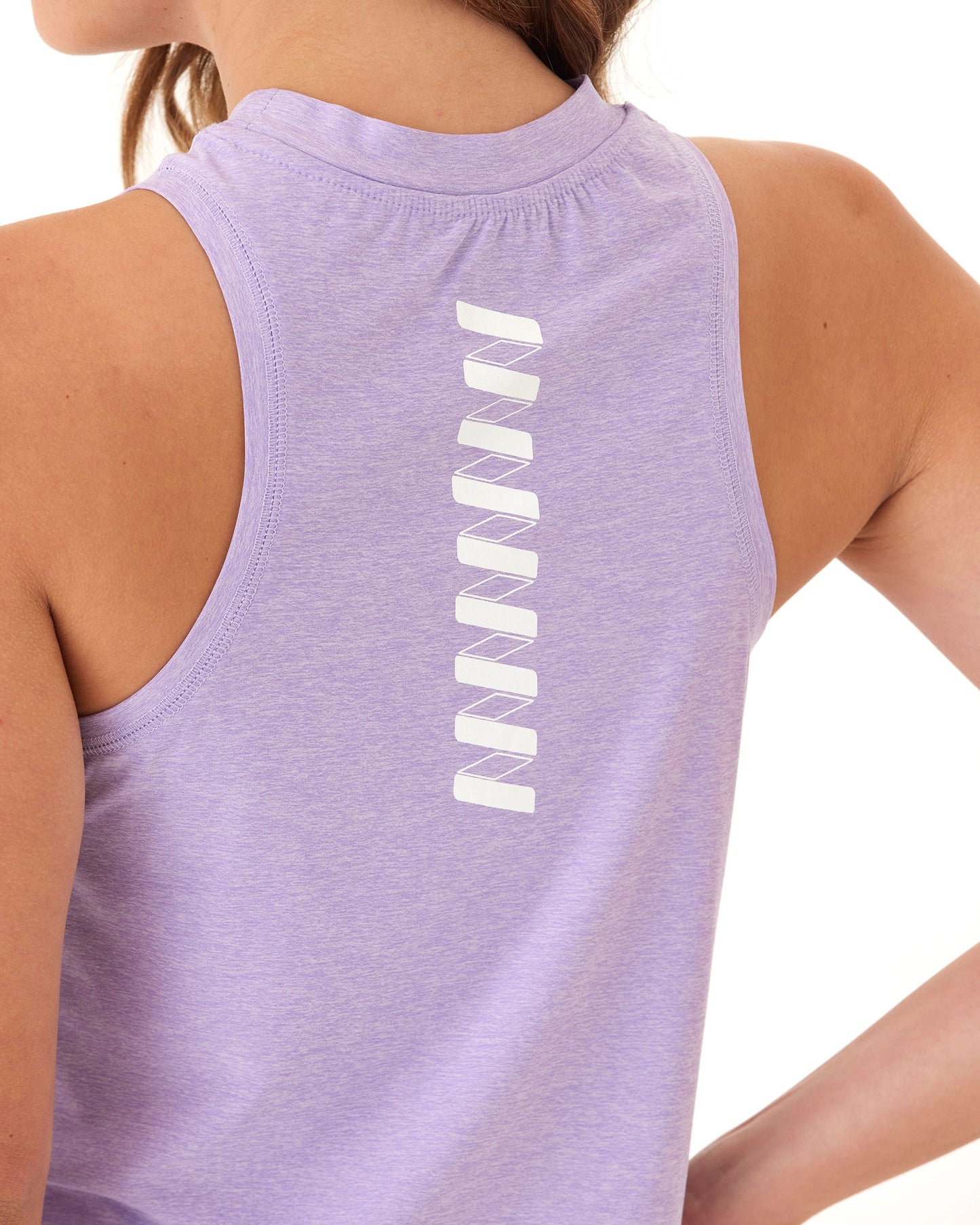 A person wears the Wringer Wear Women's Performance Logo Tank, a sleeveless light purple workout top with a vertical white geometric bar design on the upper back; only part of their hair and face is visible as their right arm is bent.