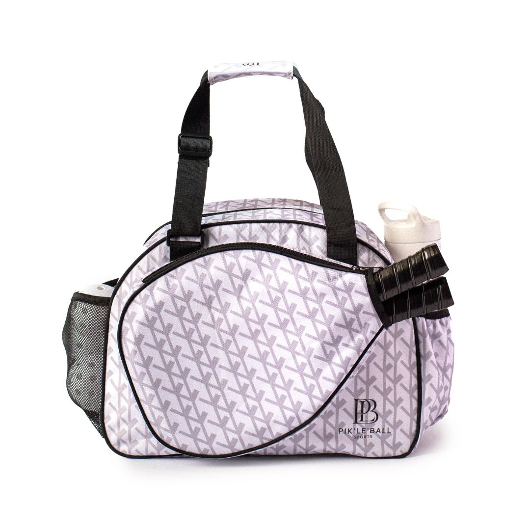 The Court Couture White Premium Women's Pickleball Bag by Pik'le'Ball Sports features a gray geometric pattern, black handles and trim, mesh, and exterior pockets—ideal for court gear. The Pickleball Bella logo accents the lower front corner.