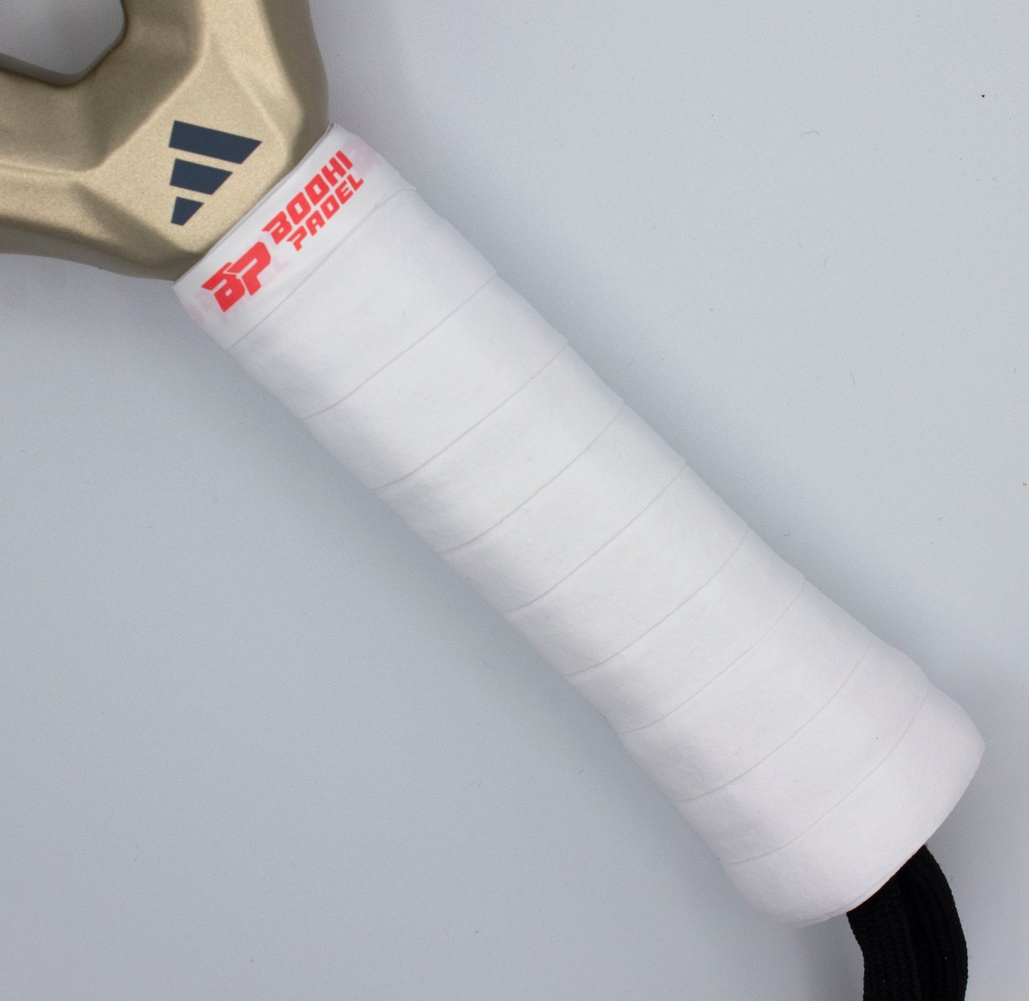 Close-up of a white, textured DRYtack™ Premium Padel Overgrip by Bodhi Performance, designed for moisture control on a padel racket handle with a black wrist strap, set against a light background.
