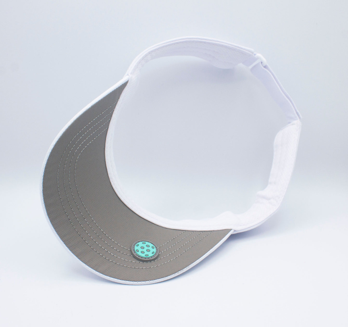 The Bodhi Performance ICON Visor is a white visor with a blue button, ideal as a performance accessory for active days or your next pickleball match.