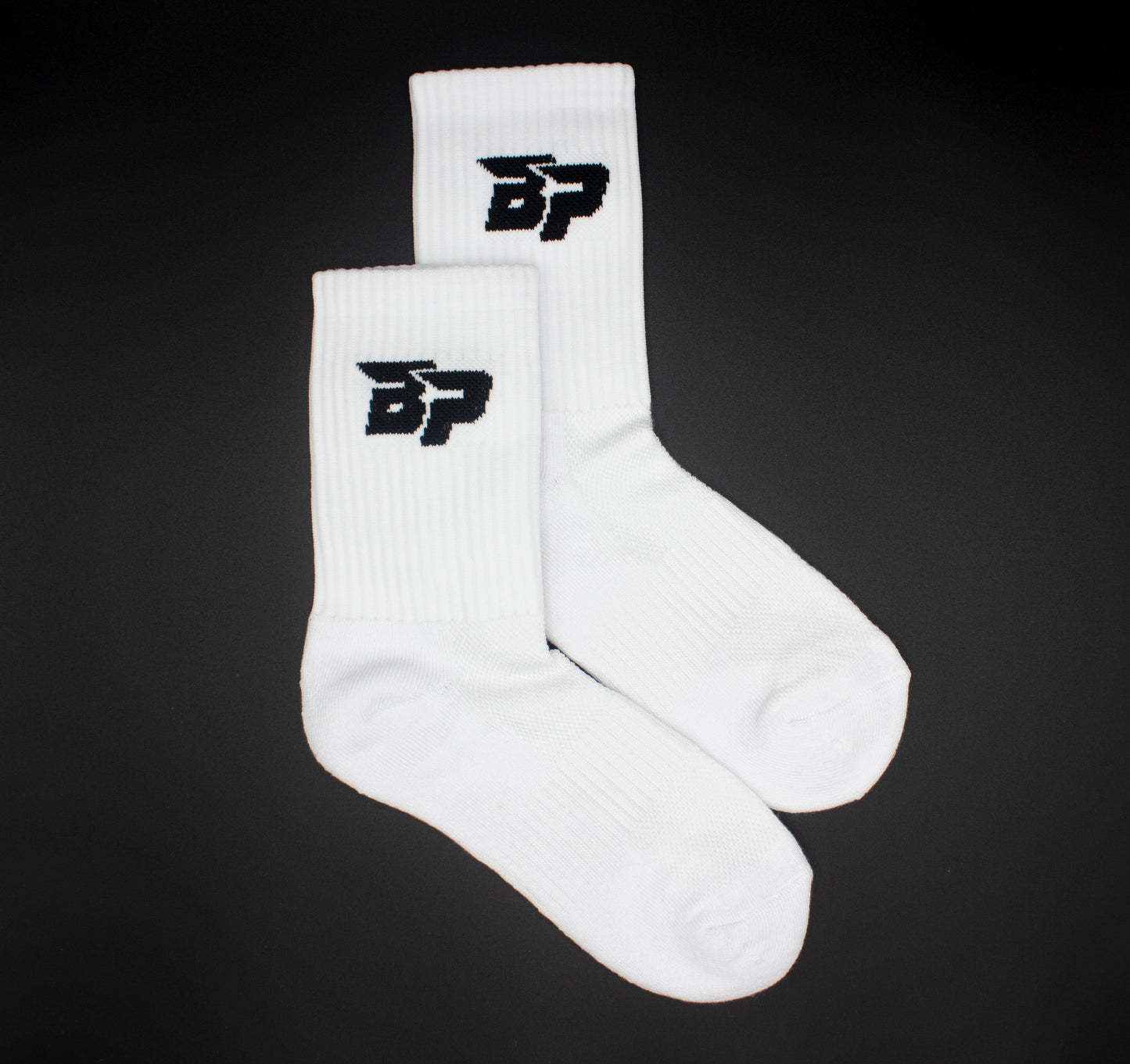 A pair of white Bodhi Performance "Performance Socks" feature a black stylized BP logo near the top. The ribbed crew socks are neatly arranged on a solid black background, slightly overlapping for a breathable, supportive look.