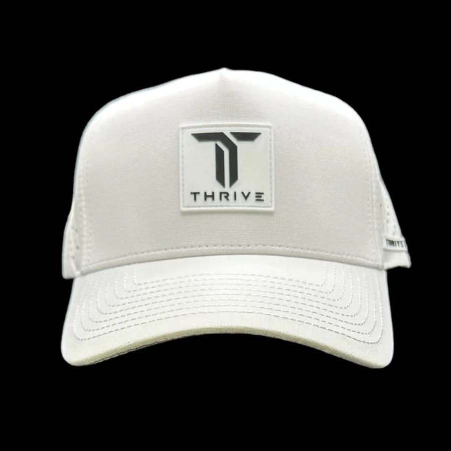 The Thrive Pickleball Elite Tour Hat is white with a structured front, features a rectangular patch with a bold T and "THRIVE" in black, visible stitching, and a mesh back, shown against a solid black background.