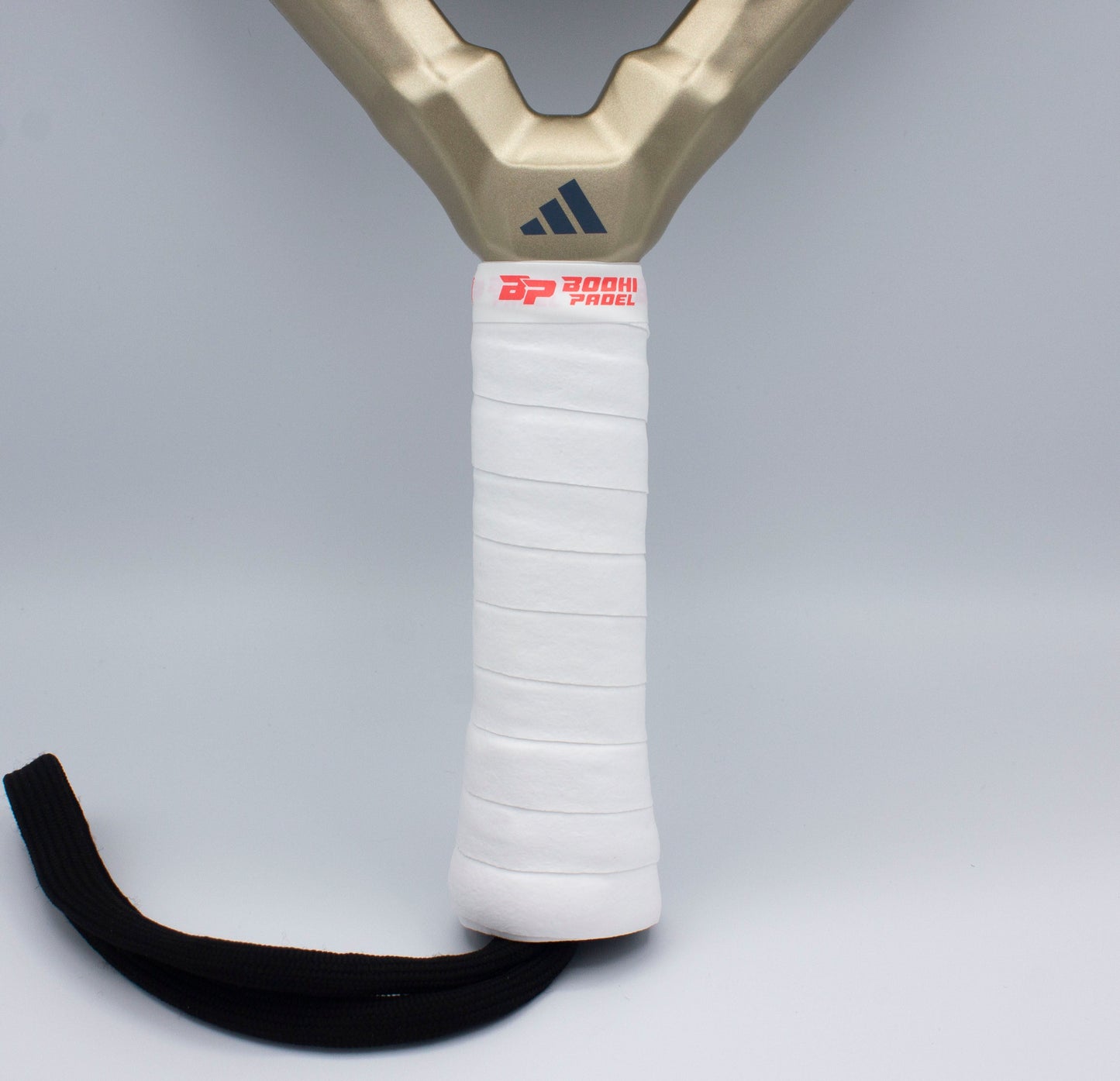 Close-up of a padel racket handle wrapped in a Bodhi Performance DRYtack™ Premium Padel Overgrip for moisture control. A black wrist strap is attached at the base. The background is plain light gray.