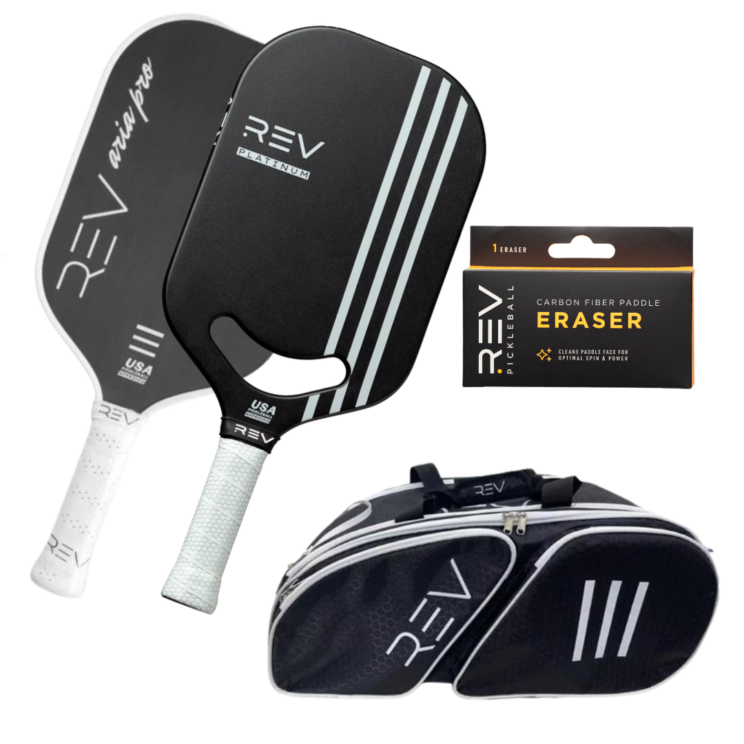 The REV Pickleball Professional - Mix & Match - Bundle for 2 includes two black paddles with white grips and angled stripes, a carbon fibre paddle eraser in a black box, and a black sports bag with white accents, displayed on a white background.
