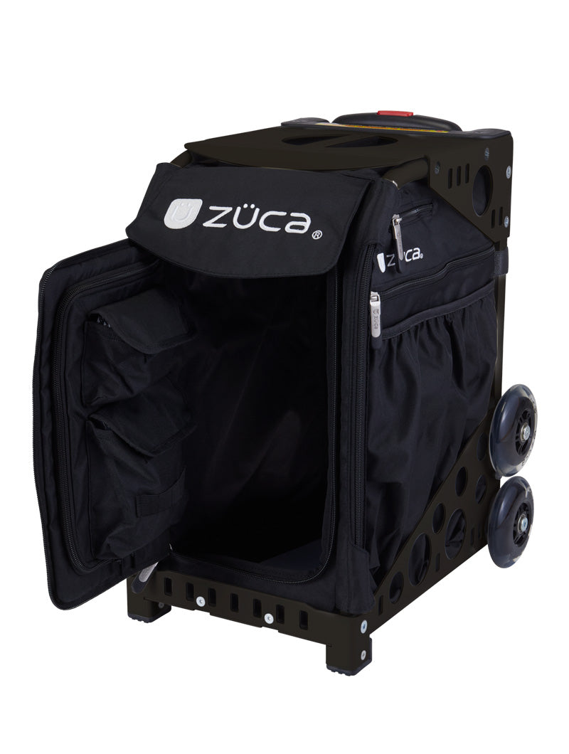 The ZUCA Pickleball Sport Black/Black bag features large wheels, a telescoping handle, a front zippered flap revealing interior storage compartments, and a side zip pocket. The bag stands upright on a white background.