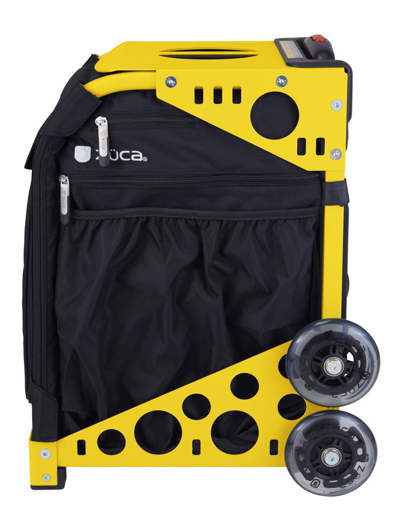 The ZUCA Pickleball Sport Black/Black bag features a yellow metal frame with circular cutouts, two large clear wheels on one side, black zippered fabric pockets, and a top plastic handle—perfect for organized pickleball storage.