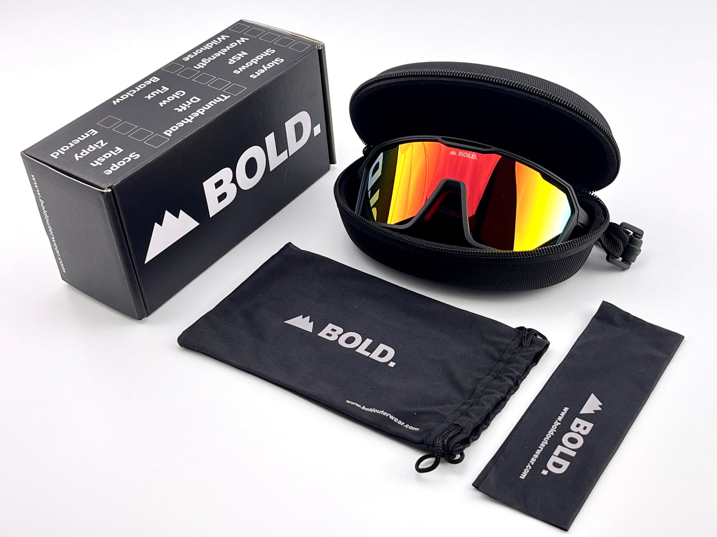 BOLD Flux Performance Sunglasses by boldouterwear: mirrored wraparound eyewear with a red-orange tint, shown in a black zippered case alongside a branded box, soft pouch, and lens cloth—designed for stylish UV protection in MTB, ski, and lifestyle settings.