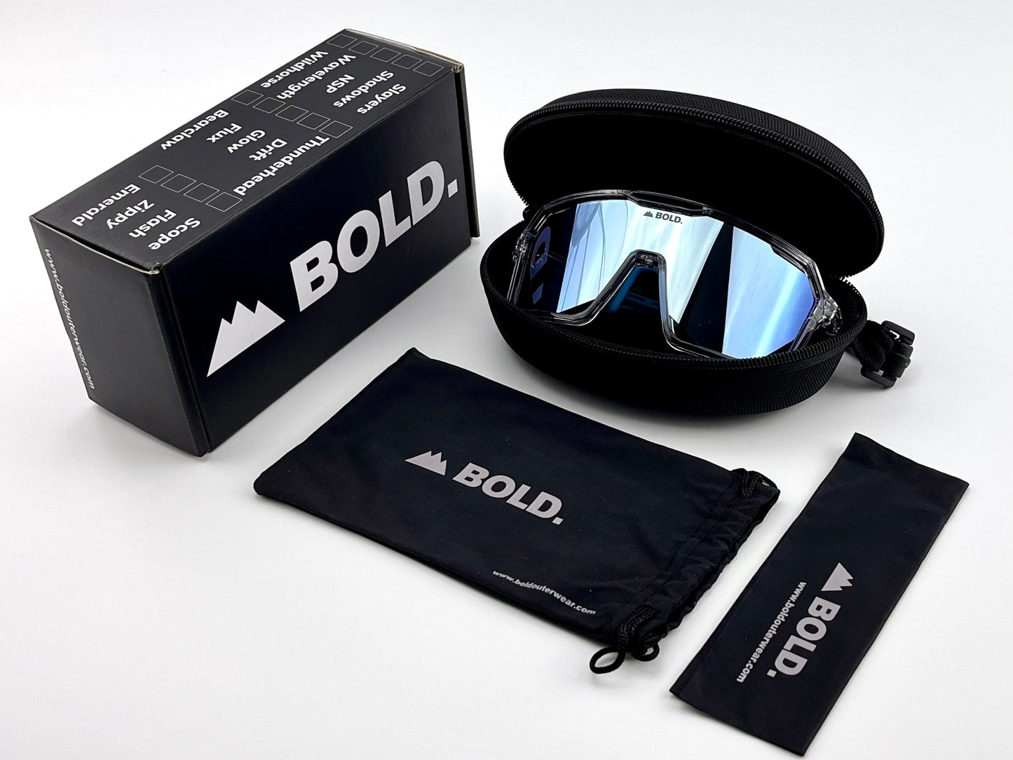 BOLD Flux Performance Sunglasses by boldouterwear, featuring UV protection and mirrored blue-tinted wraparound lenses, are displayed with a hard black case, branded box, drawstring pouch, and cleaning cloth on a white background.