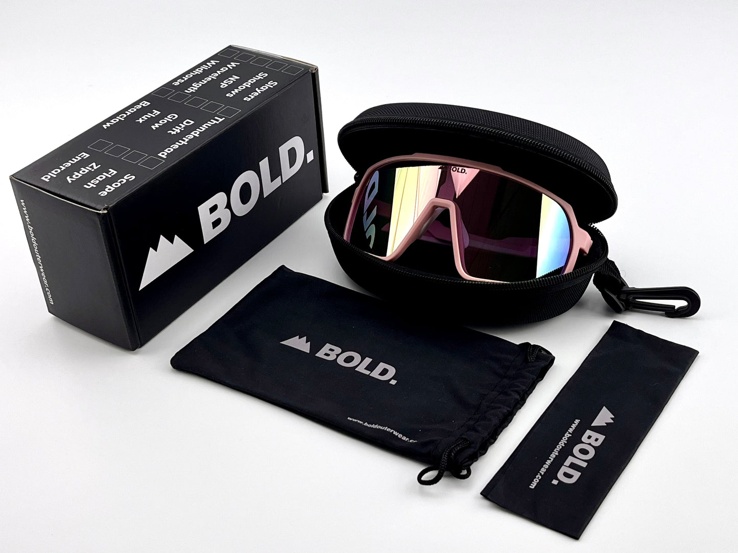 A pair of BOLD Slayers Performance Sunglasses by boldouterwear, featuring pink mirrored wraparound lenses, rest in an open black zip case beside a branded box, drawstring pouch, and cleaning cloth on a white surface.
