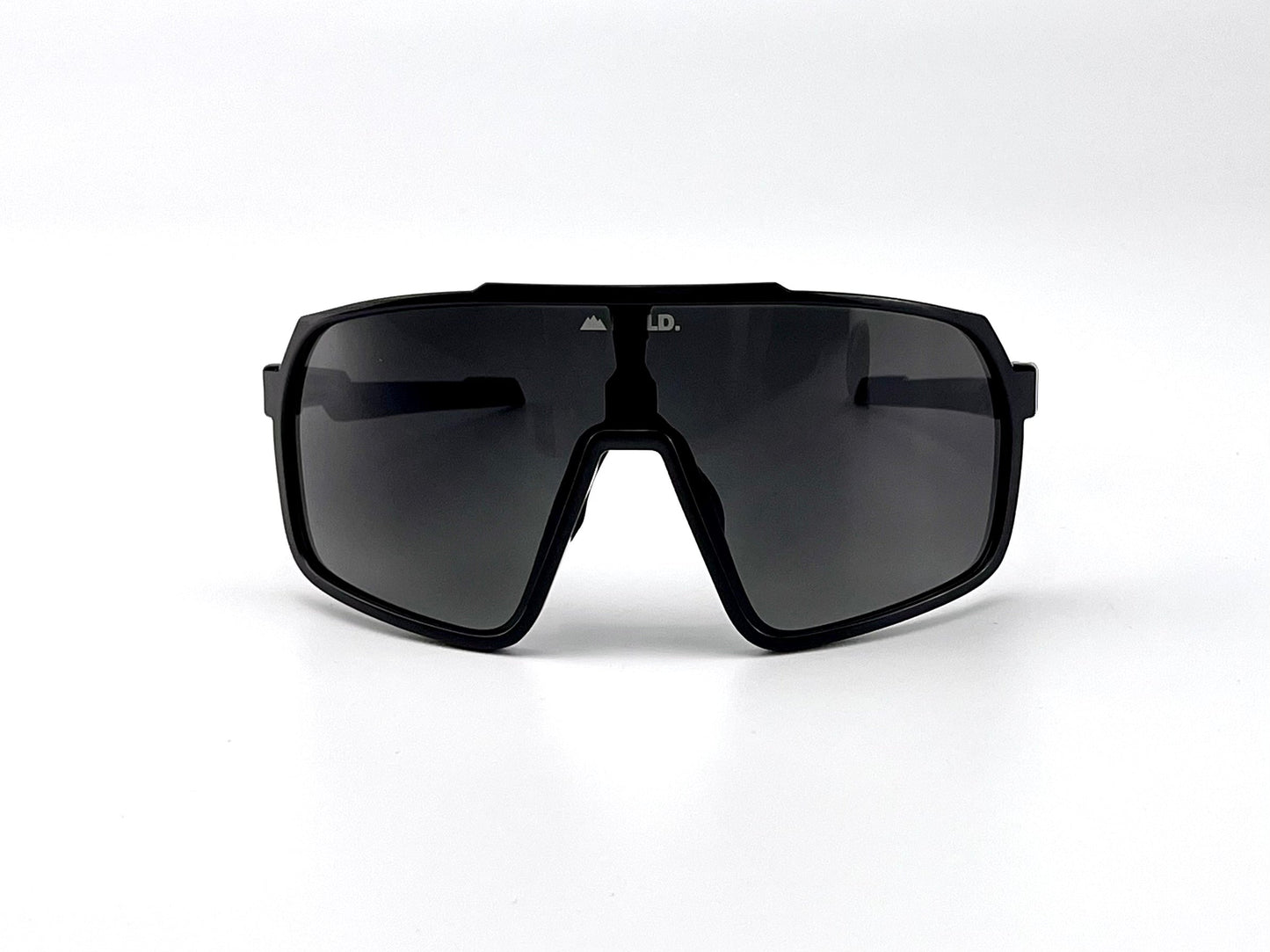 The BOLD Slayers Photochromic Sunglasses by boldouterwear feature a single large dark lens and thick angular frame, shown in black facing forward against a white background. Ideal for MTB, ski, and lifestyle wear.