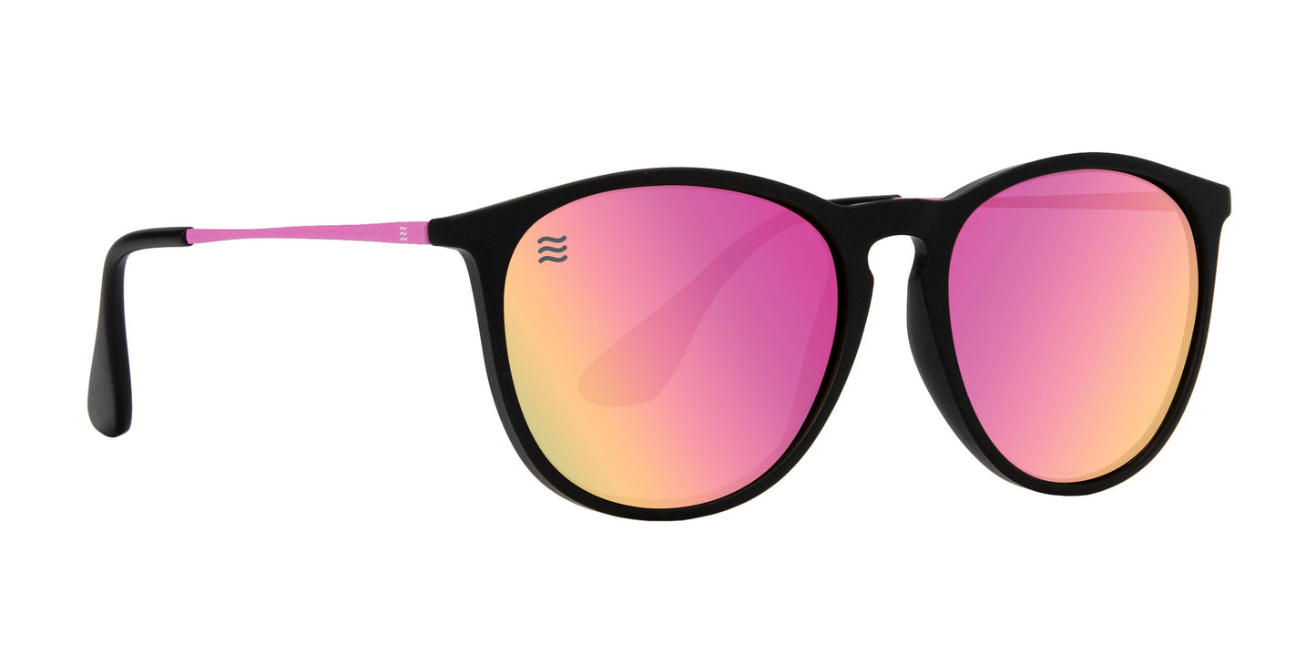 The Neven Eyewear Quinn sunglasses feature round black TR90 frames, pink stainless steel arms, and mirrored lenses in pink, yellow, and orange hues with a small wavy logo on the left lens. Shown against a plain white background.