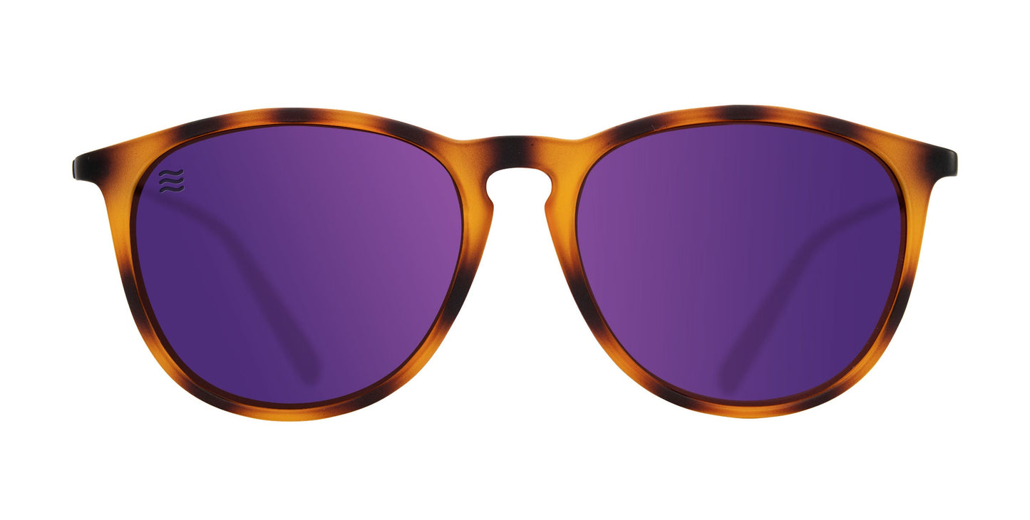 The Neven Eyewear Stella sunglasses feature a round, brown tortoiseshell TR90 frame with solid purple polarized lenses and a subtle wavy logo etched on the left lens, presented on a white background.