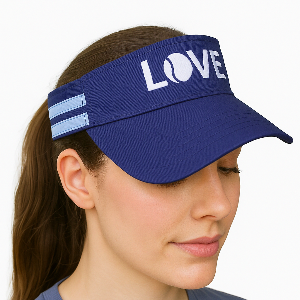 A woman with long brown hair in a ponytail wears the Striped Cotton Canvas LOVE Visor by Runway Athletics—navy with white "LOVE" and a tennis ball graphic—paired with a blue shirt, facing slightly down with a neutral expression.