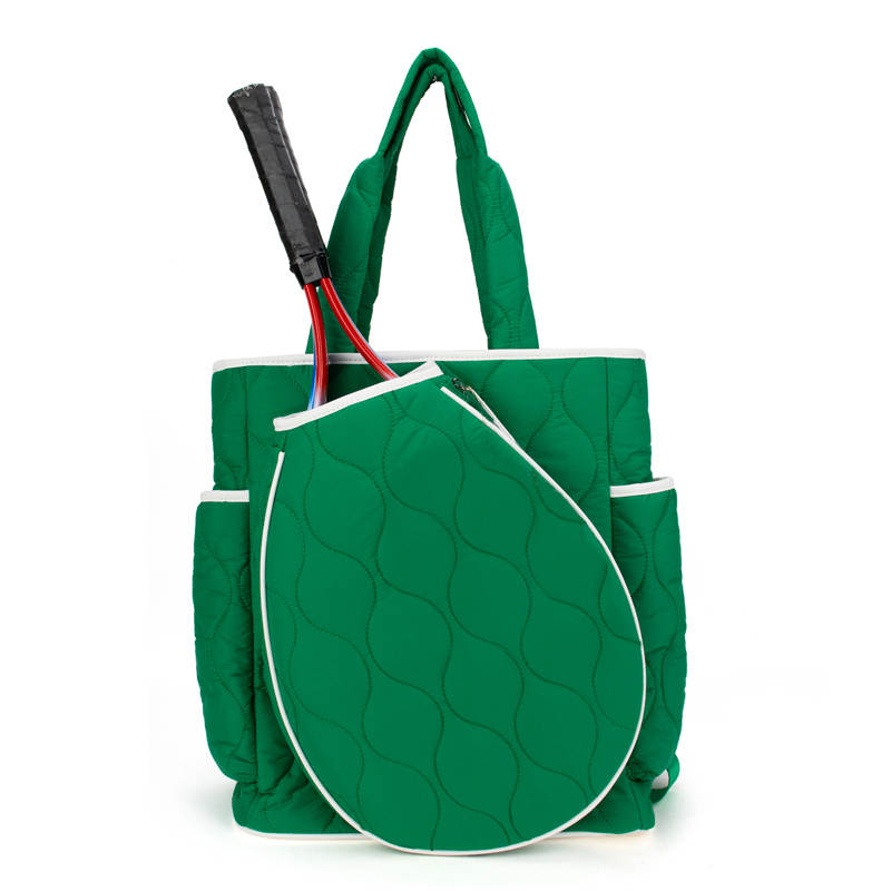 The Queen of the Court Park Ave Tennis Convertible Bag/Backpack is a green quilted tennis bag with white trim, side pockets, black handles, an attached racquet case for two racquets, and stands upright on a white background.